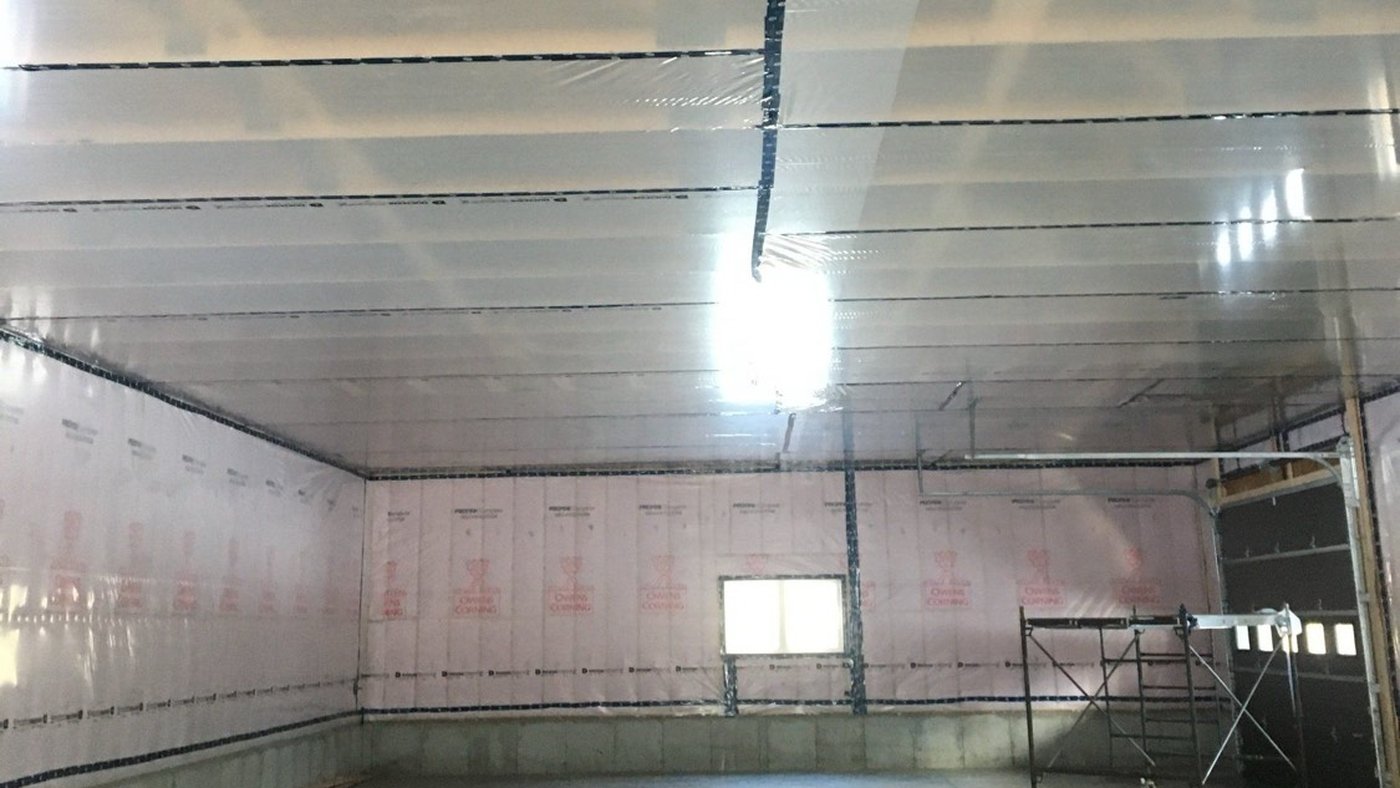Shop interior with batts behind poly on the walls and ceiling, every ceiling lap taped and the wall sheet taped along the top plate, the detailing a 6 mil poly vapour barrier needs to pass as the air barrier