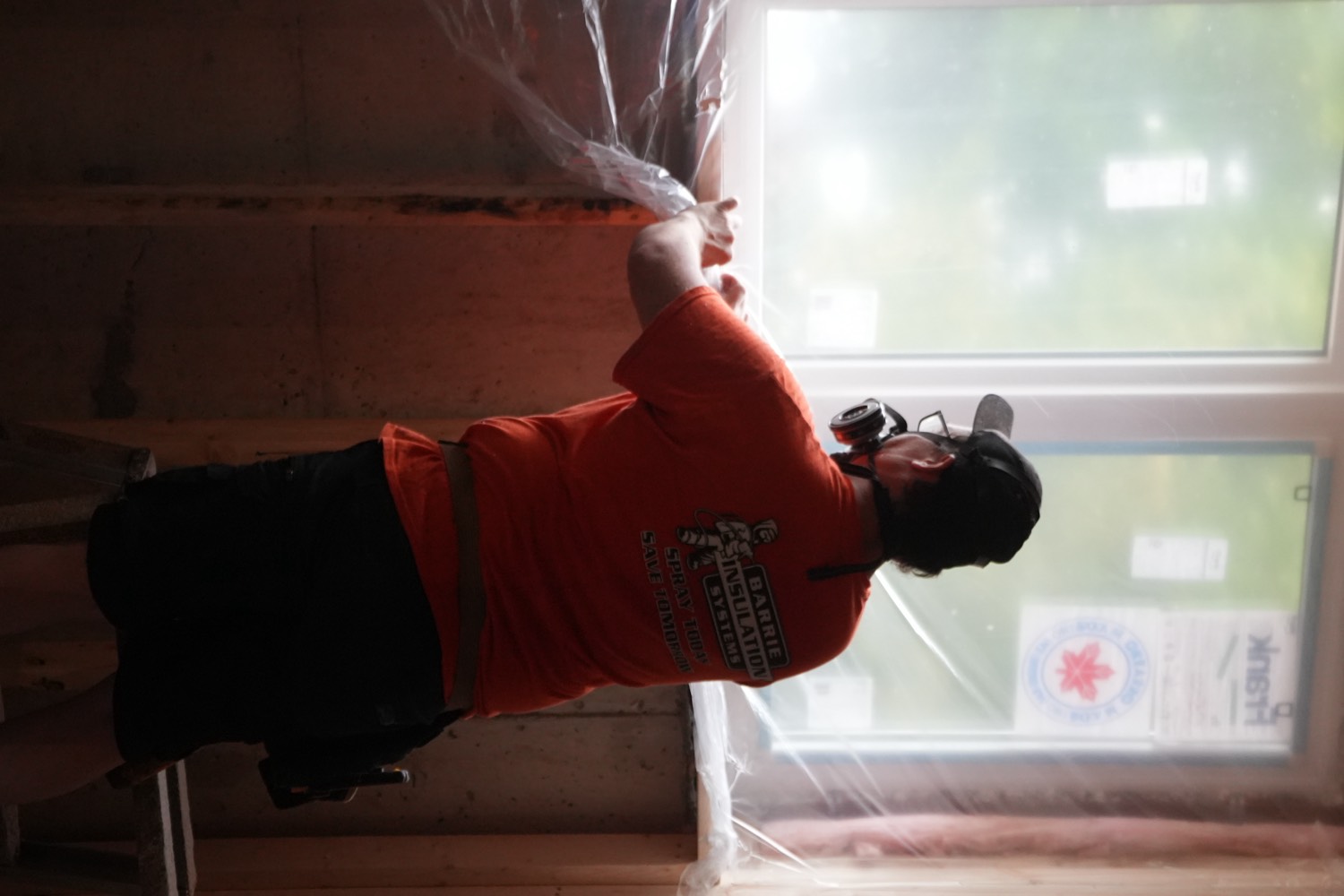 Crew member masking a window with plastic sheeting before spraying