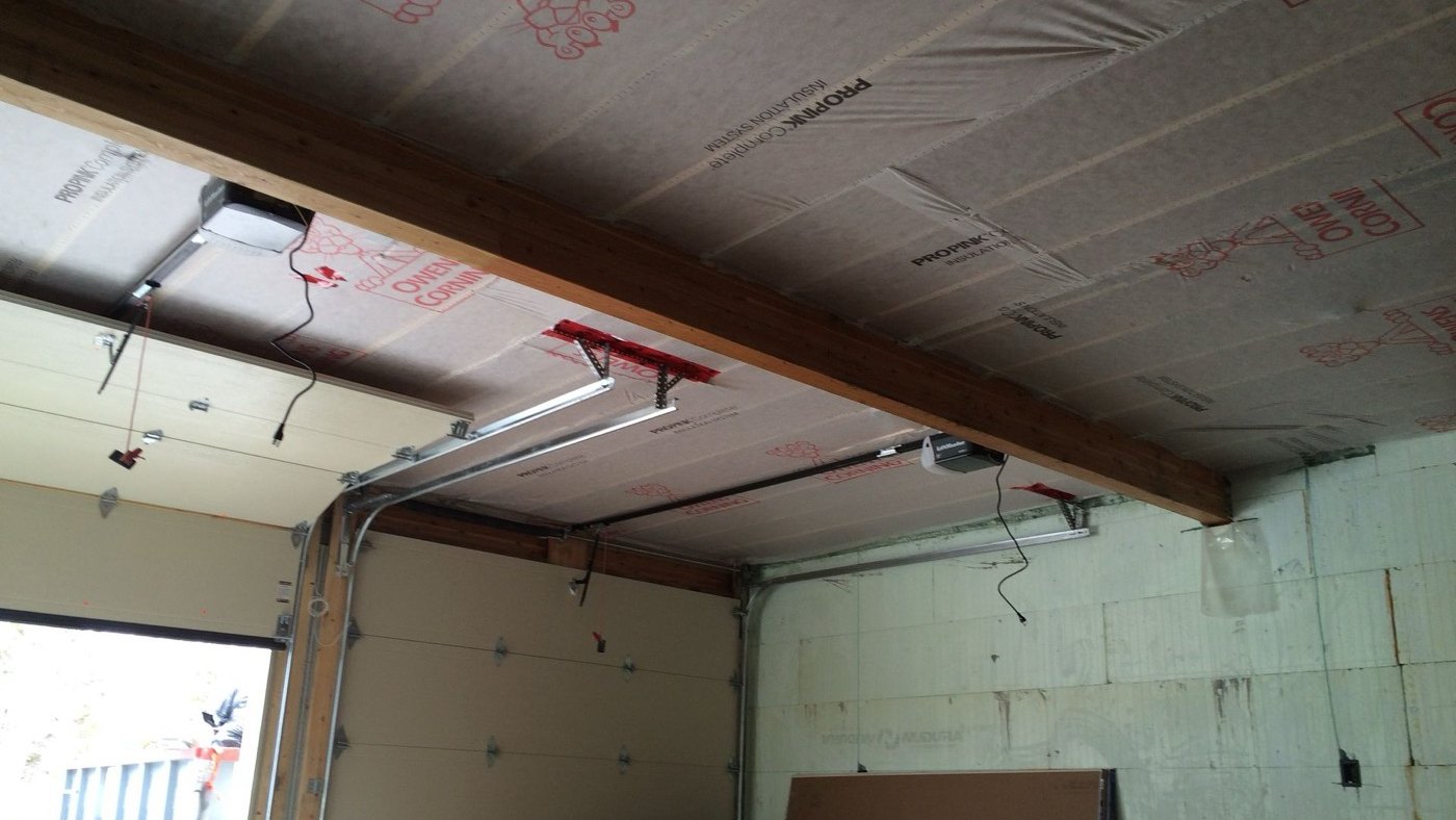 Garage with the ceiling and walls insulated so the space can be heated, the overhead doors still open to the yard