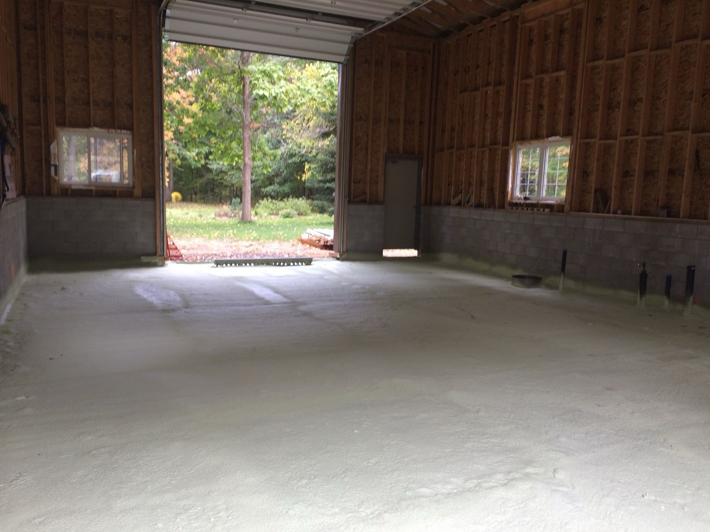 Framed walls seen from inside before insulation, with the OSB sheathing exposed between the studs above a concrete block knee wall