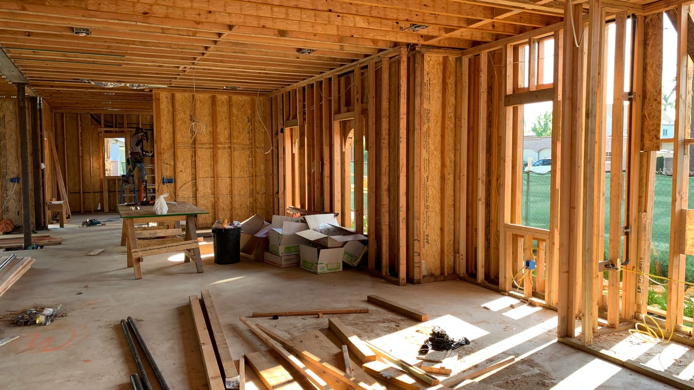 New-build interior with framed exterior walls, OSB sheathing and electrical rough-in complete, window openings framed, and no insulation installed yet
