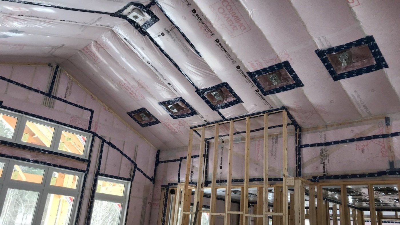 Cathedral ceiling and walls of a new build with batts behind taped polyethylene, the default assembly a smart vapour barrier is measured against, with sealed boxes at each ceiling fixture