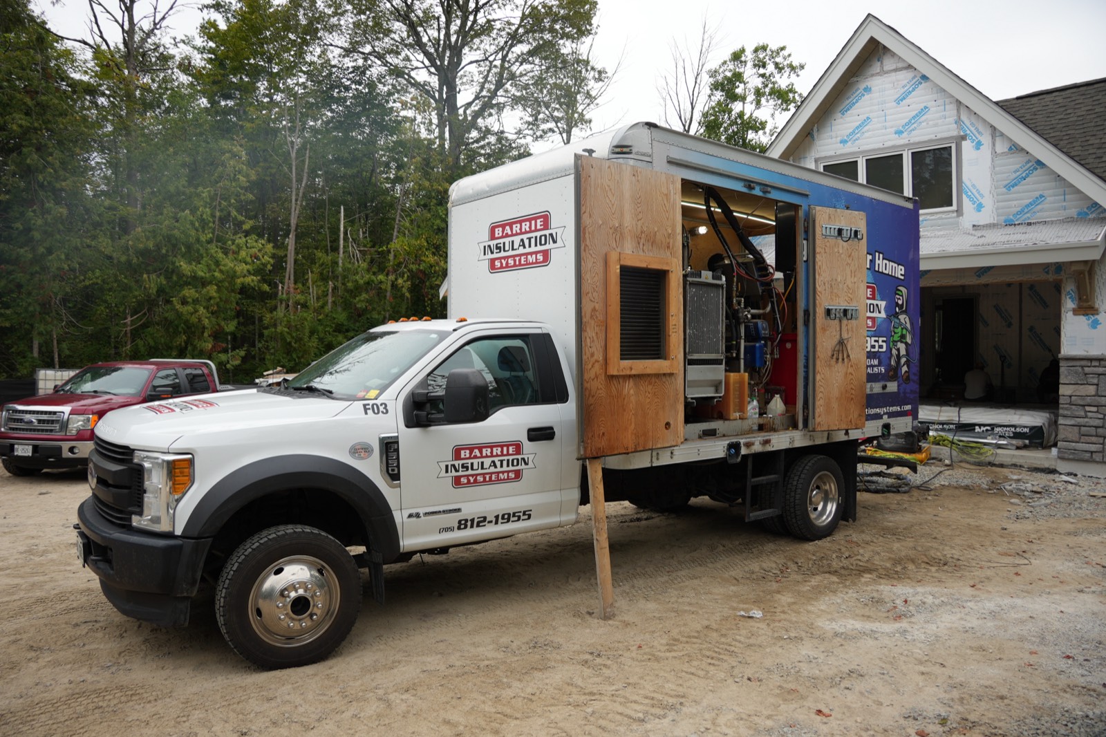 Insulation truck with the rig open beside a house under construction