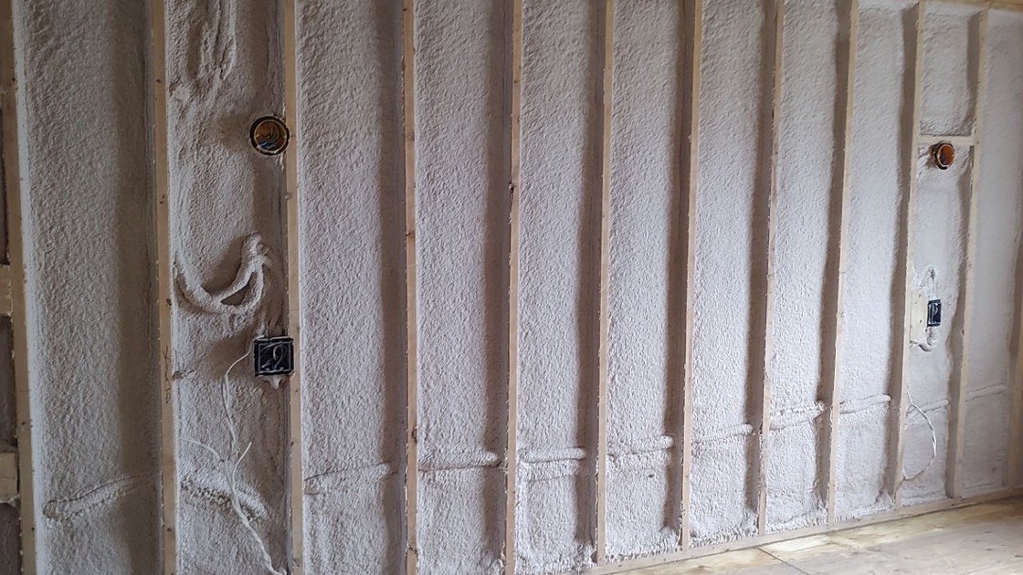 Vapour barrier vs air barrier in one layer: exterior wall of a new build with spray foam filling every stud bay and bonded to the bottom plate, electrical boxes and wiring already roughed in through the foam