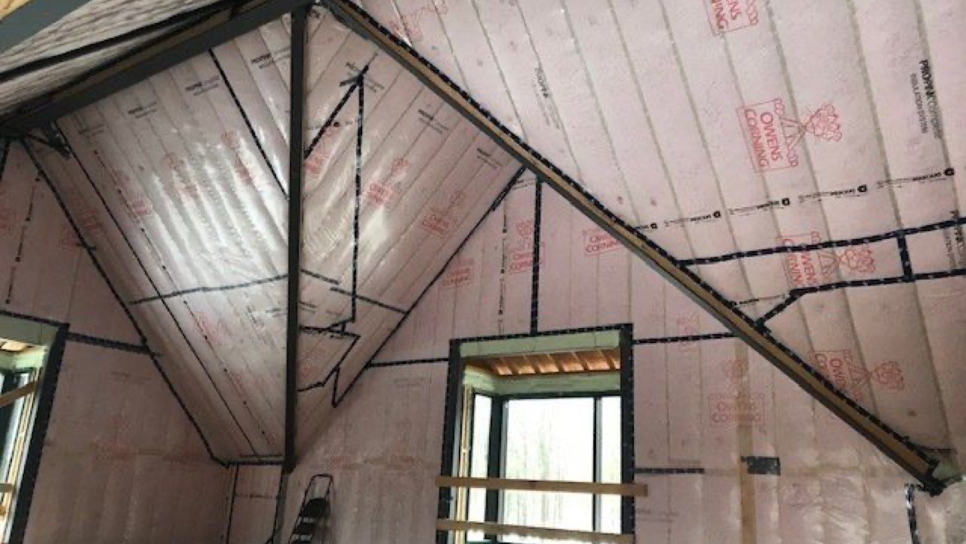 Vapour barrier vs air barrier on one sheet: pink batts behind clear poly on a sloped ceiling and gable wall, every lap, the knee wall and the window opening sealed in black tape